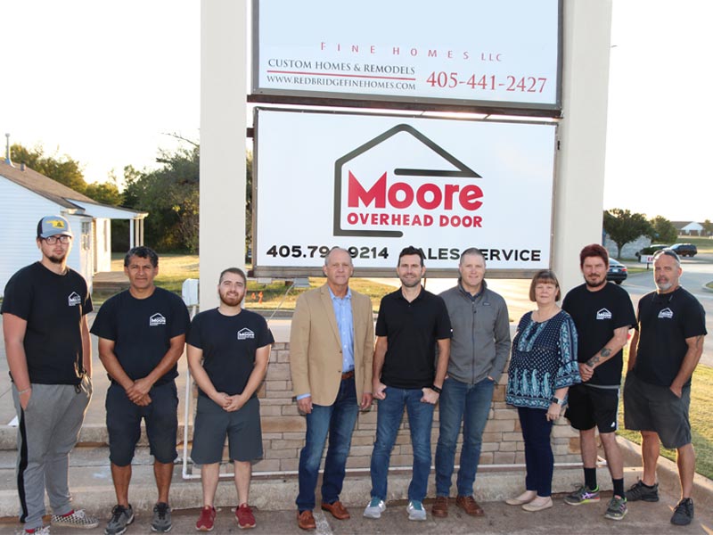 The Moore Overhead Garage Door team standing in front of the company sign.